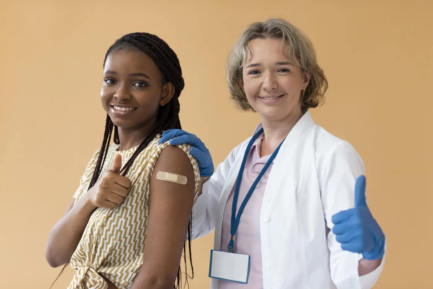 Une adolescente vaccinée, pansement au bras, aux côtés d'une professionnelle de santé