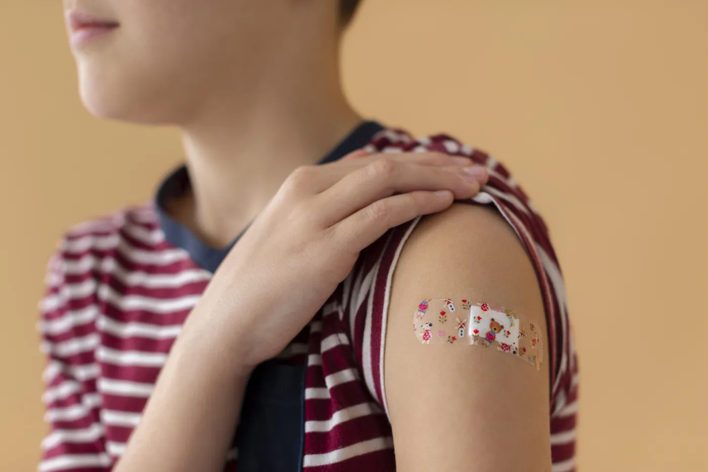 Gros plan sur le bras d'un enfant portant un pansement après une vaccination contre le papillomavirus