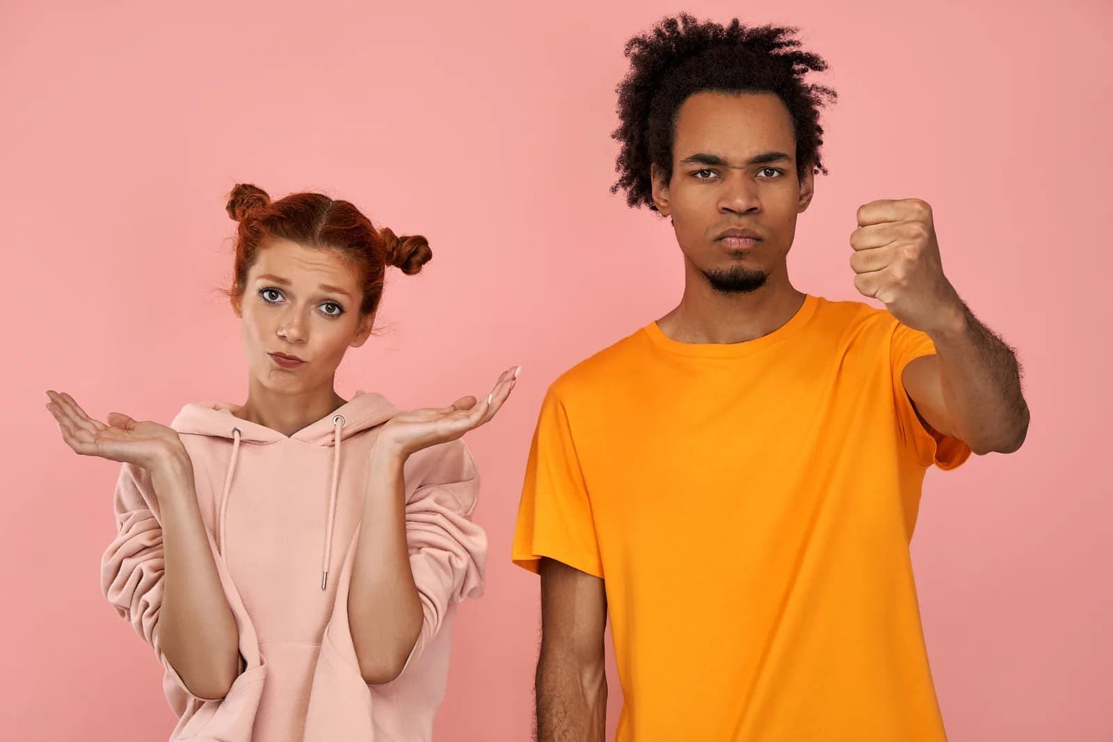 Deux parents, l'une les mains ouvertes, l'autre le poing levé